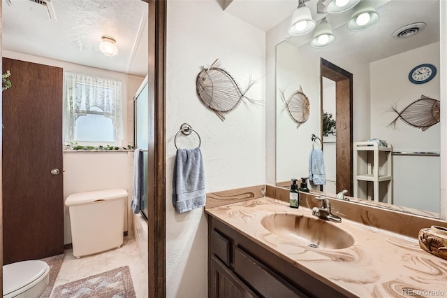 full bathroom with tile patterned flooring, bath / shower combo with glass door, a textured ceiling, toilet, and vanity