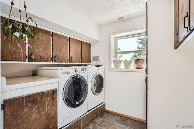 washroom with washer and clothes dryer, cabinets, and a textured ceiling