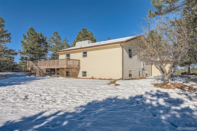 snow covered rear of property featuring a deck