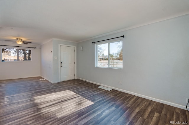 empty room with crown molding, a healthy amount of sunlight, dark wood-type flooring, and ceiling fan