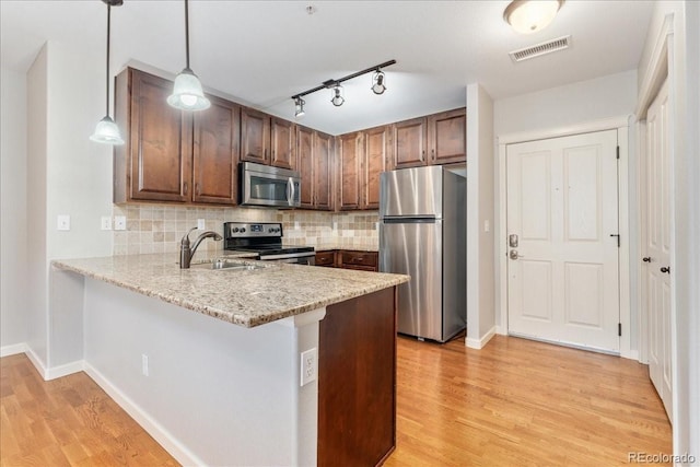 kitchen with hanging light fixtures, appliances with stainless steel finishes, sink, and kitchen peninsula