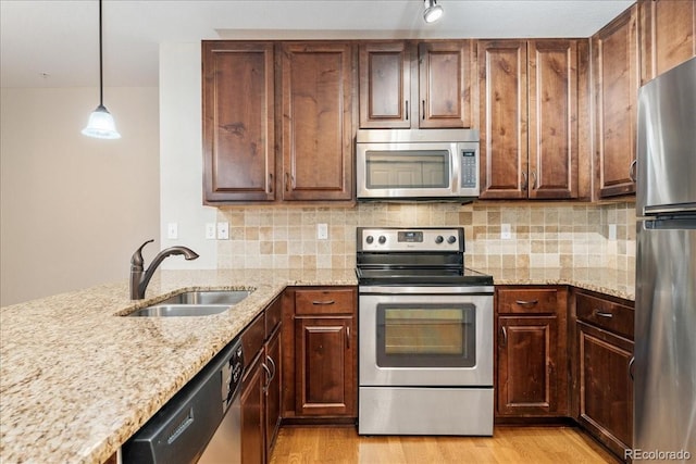 kitchen featuring pendant lighting, stainless steel appliances, sink, and light hardwood / wood-style flooring