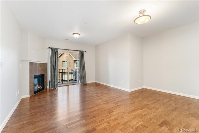 unfurnished living room with a tiled fireplace and hardwood / wood-style flooring