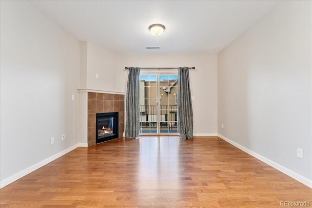 unfurnished living room featuring a tiled fireplace and light hardwood / wood-style flooring