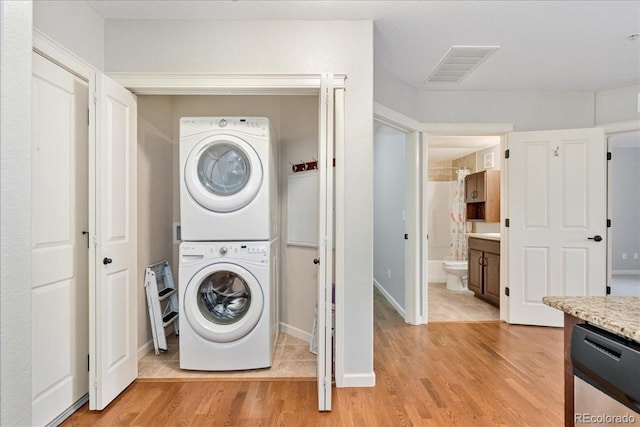 washroom featuring stacked washer and clothes dryer and light hardwood / wood-style flooring