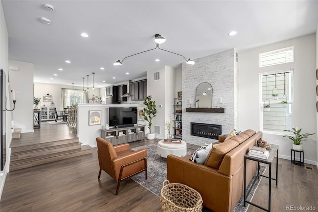 11027 Sunshimmer Cir, Parker, CO 80134 - living area with a stone fireplace, dark wood-style floors, healthy amount of natural light, recessed lighting, and stairway