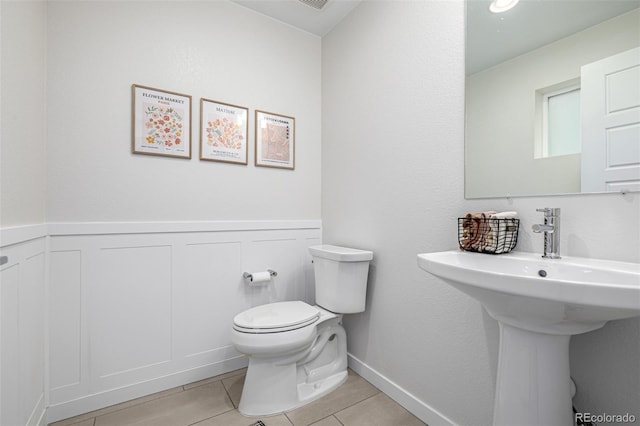 11027 Sunshimmer Cir, Parker, CO 80134 - bathroom with toilet, tile patterned floors, wainscoting, and a sink