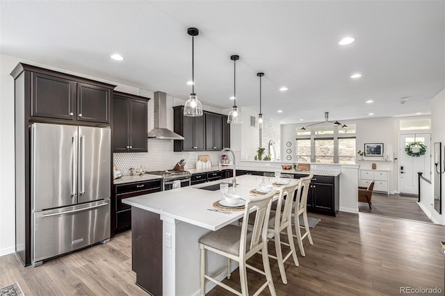 11027 Sunshimmer Cir, Parker, CO 80134 - kitchen featuring stainless steel appliances, wall chimney range hood, a sink, wood finished floors, and light countertops