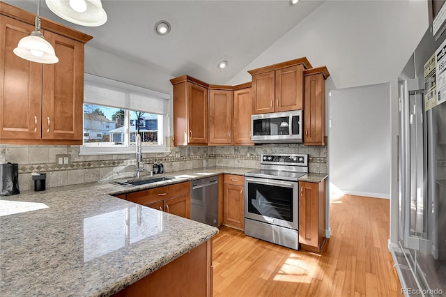 kitchen with light wood-style flooring, a sink, light stone counters, stainless steel appliances, and brown cabinetry