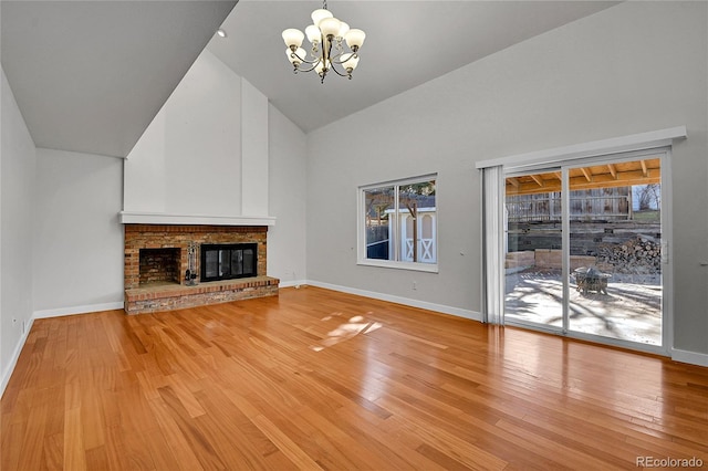 unfurnished living room with a chandelier, high vaulted ceiling, baseboards, and wood finished floors