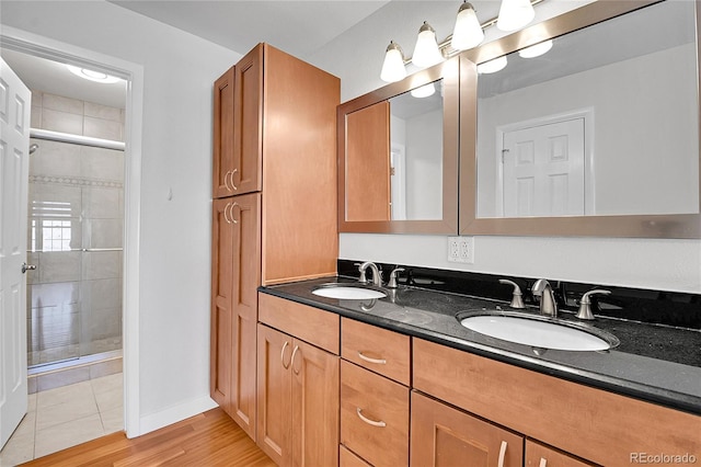 full bath featuring double vanity, a stall shower, and a sink