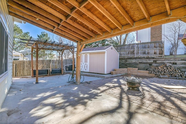 view of patio / terrace with a fenced backyard, a shed, a fire pit, and an outdoor structure