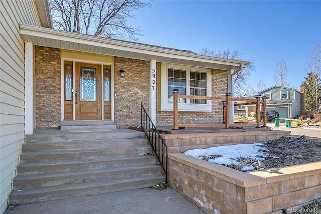 entrance to property with covered porch and brick siding