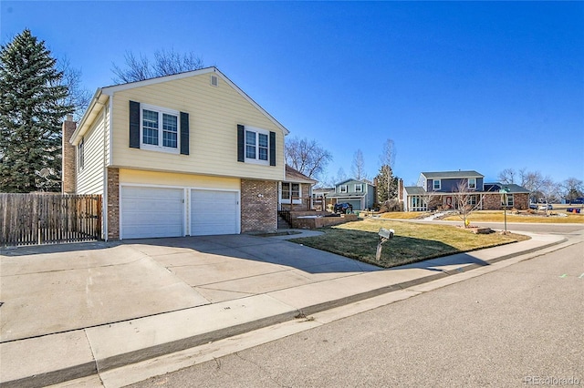 view of front facade featuring a front lawn, fence, concrete driveway, an attached garage, and brick siding