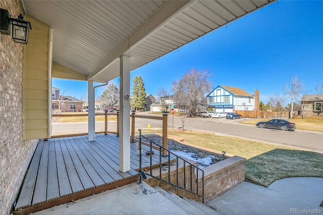 wooden terrace with a yard, covered porch, and a residential view