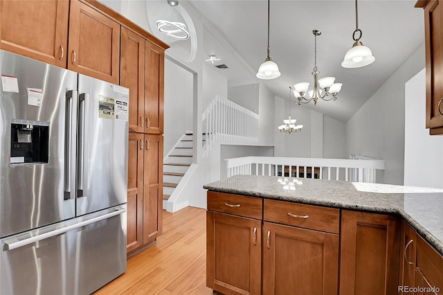 kitchen featuring brown cabinets, an inviting chandelier, stainless steel refrigerator with ice dispenser, decorative light fixtures, and light wood-type flooring