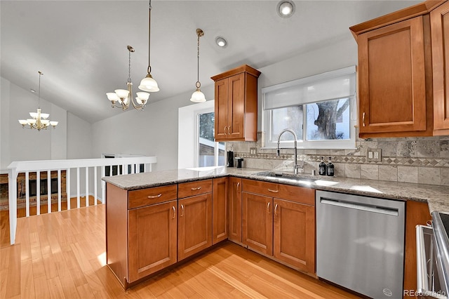 kitchen with brown cabinetry, a peninsula, a sink, stainless steel appliances, and a notable chandelier