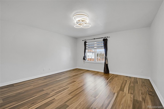 empty room featuring visible vents, baseboards, and wood finished floors