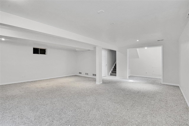 finished basement with stairs, visible vents, and baseboards