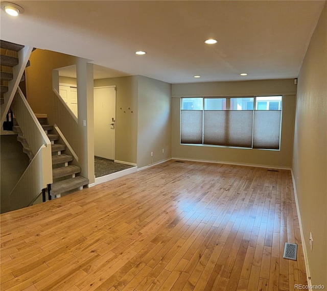 unfurnished room with stairs, hardwood / wood-style floors, visible vents, baseboards, and recessed lighting
