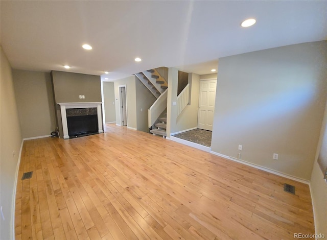 unfurnished living room with light wood finished floors, stairs, and visible vents
