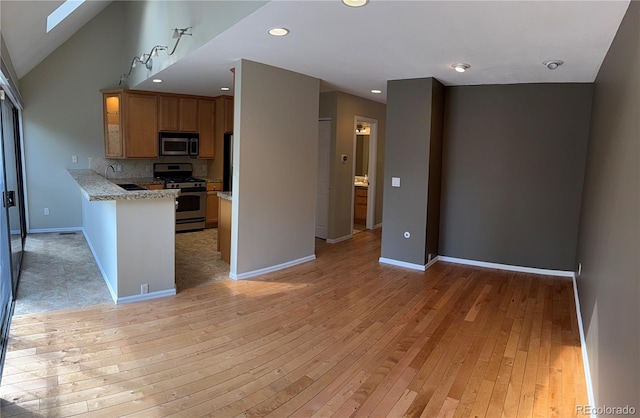 kitchen with recessed lighting, baseboards, light wood finished floors, stainless steel appliances, and a skylight