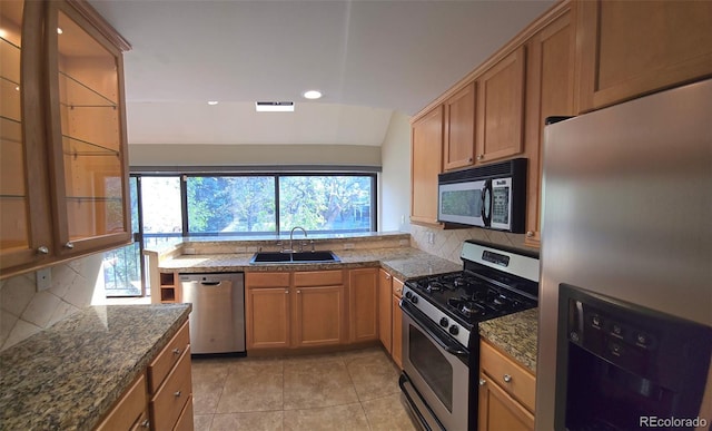 kitchen featuring lofted ceiling, light tile patterned flooring, a sink, decorative backsplash, and appliances with stainless steel finishes