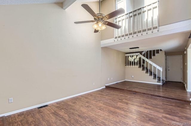 unfurnished living room featuring beamed ceiling, ceiling fan with notable chandelier, dark hardwood / wood-style flooring, and high vaulted ceiling