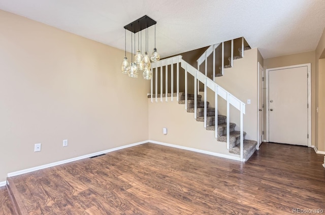 interior space featuring a textured ceiling, dark hardwood / wood-style flooring, and an inviting chandelier