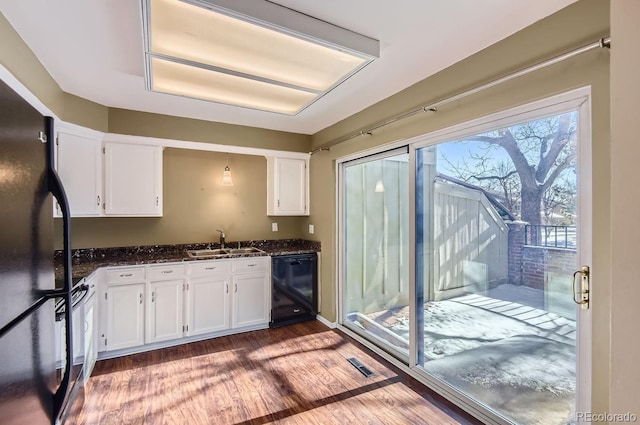 kitchen featuring dishwasher, refrigerator, sink, dark stone countertops, and white cabinetry