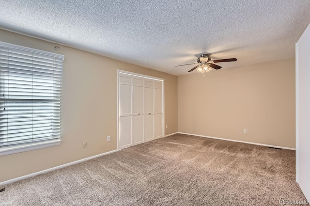 unfurnished bedroom featuring a textured ceiling, carpet floors, a closet, and ceiling fan