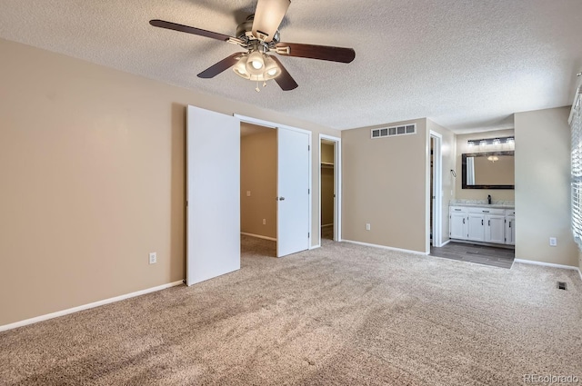 unfurnished bedroom featuring a walk in closet, carpet floors, ceiling fan, connected bathroom, and a closet