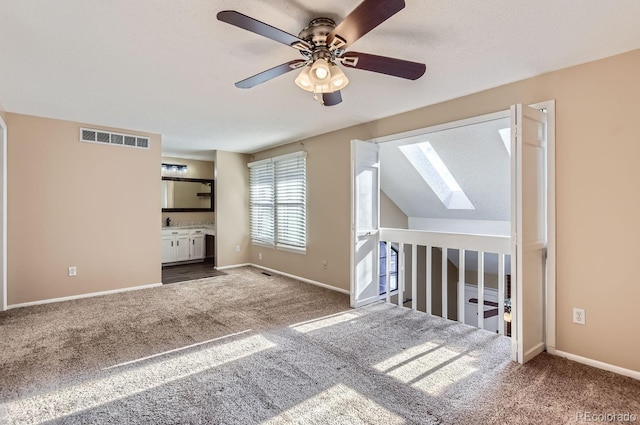 unfurnished living room featuring carpet, lofted ceiling with skylight, and ceiling fan