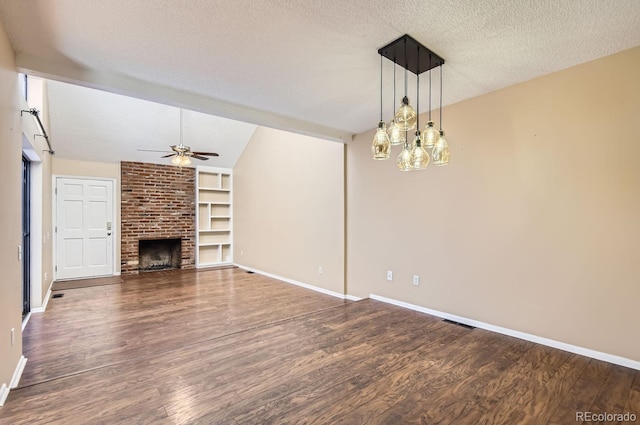 unfurnished living room featuring a textured ceiling, vaulted ceiling, ceiling fan, built in features, and a fireplace