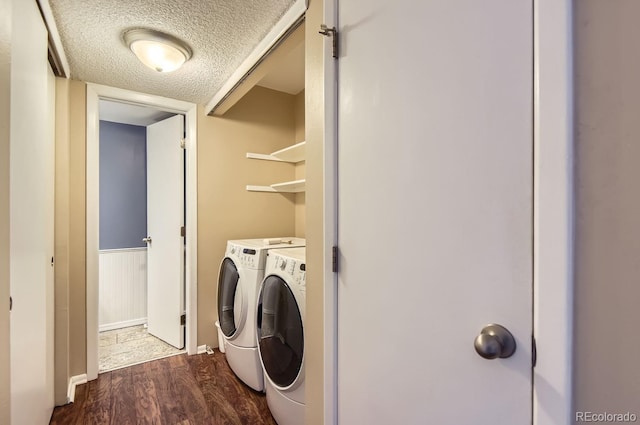 laundry area featuring a textured ceiling, dark wood-type flooring, and washing machine and clothes dryer