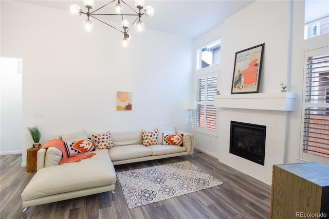 living room with a notable chandelier, dark hardwood / wood-style flooring, and a tile fireplace