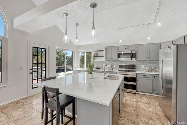 kitchen with a sink, stainless steel appliances, gray cabinets, and vaulted ceiling