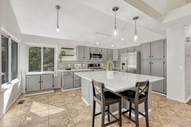 kitchen with visible vents, lofted ceiling, open shelves, gray cabinets, and appliances with stainless steel finishes