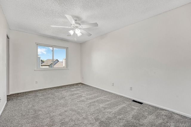 empty room featuring visible vents, a textured ceiling, carpet flooring, baseboards, and ceiling fan