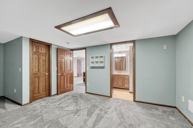 unfurnished bedroom with ensuite bath, baseboards, and light carpet