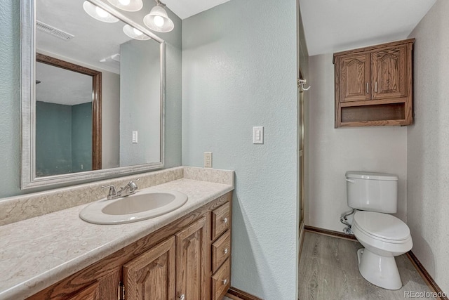 bathroom with visible vents, toilet, wood finished floors, baseboards, and vanity