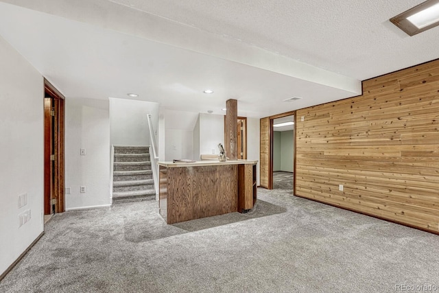 kitchen with light countertops, wooden walls, light colored carpet, and a textured ceiling