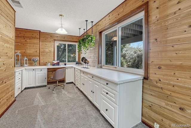 office featuring visible vents, light colored carpet, wood walls, and a textured ceiling