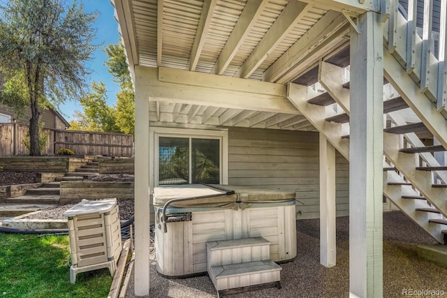 view of patio / terrace with stairway, a hot tub, and fence