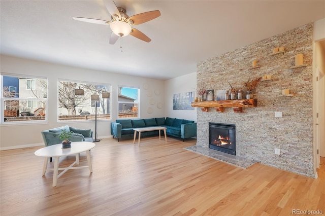 living room featuring ceiling fan, a large fireplace, hardwood / wood-style floors, and a healthy amount of sunlight