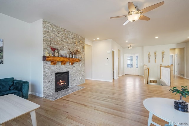 living room with ceiling fan, a fireplace, and light hardwood / wood-style floors