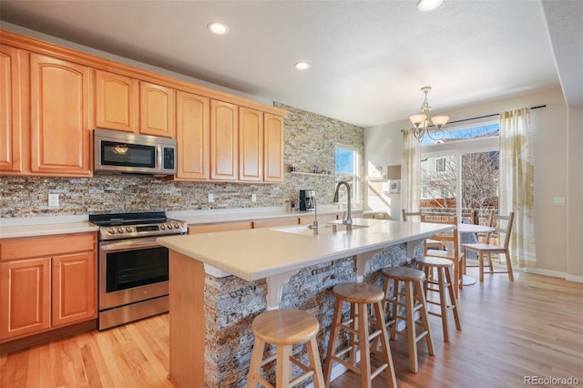 kitchen featuring decorative light fixtures, a kitchen bar, stainless steel appliances, an inviting chandelier, and a kitchen island with sink