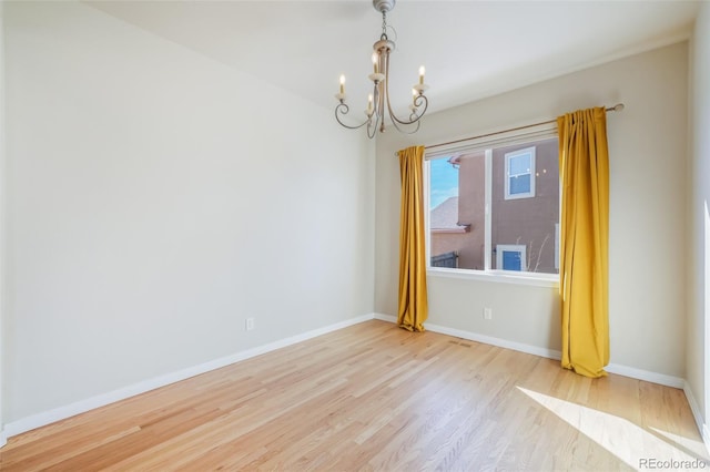 empty room with an inviting chandelier and light hardwood / wood-style flooring