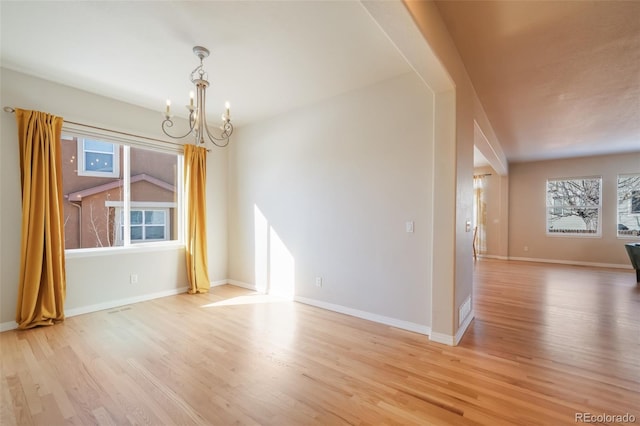 empty room with lofted ceiling, a notable chandelier, and light wood-type flooring