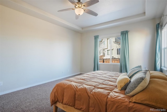 carpeted bedroom featuring ceiling fan and a tray ceiling